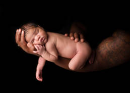 newborn baby asleep on her father's arm