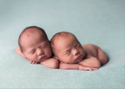 newborn twins posed side by side on aqua blanket