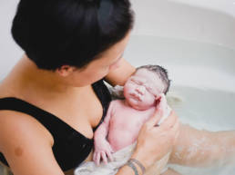 mother holds newborn in tub after waterbirth