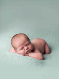 newborn baby sleeping on tummy with hands under chin